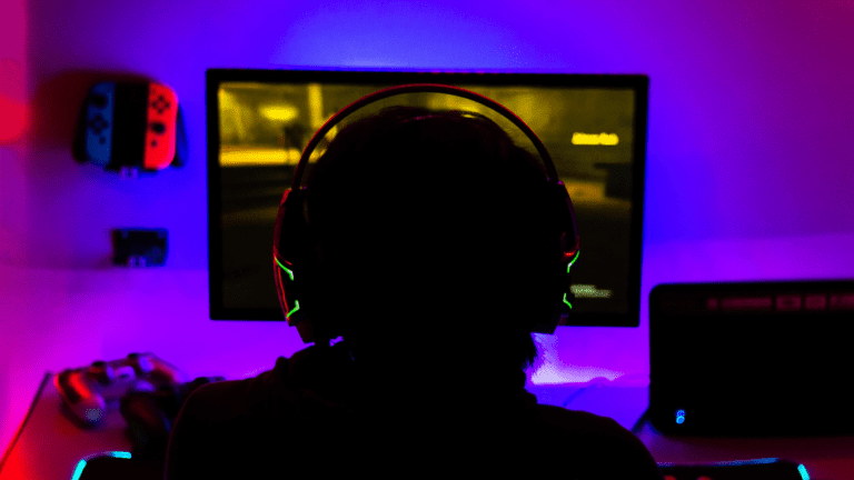 a person playing video games in a dark room with neon lights