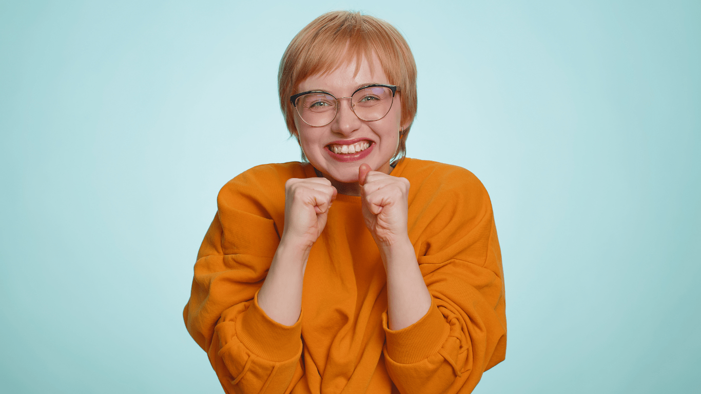 a person in glasses and an orange shirt is making a fist