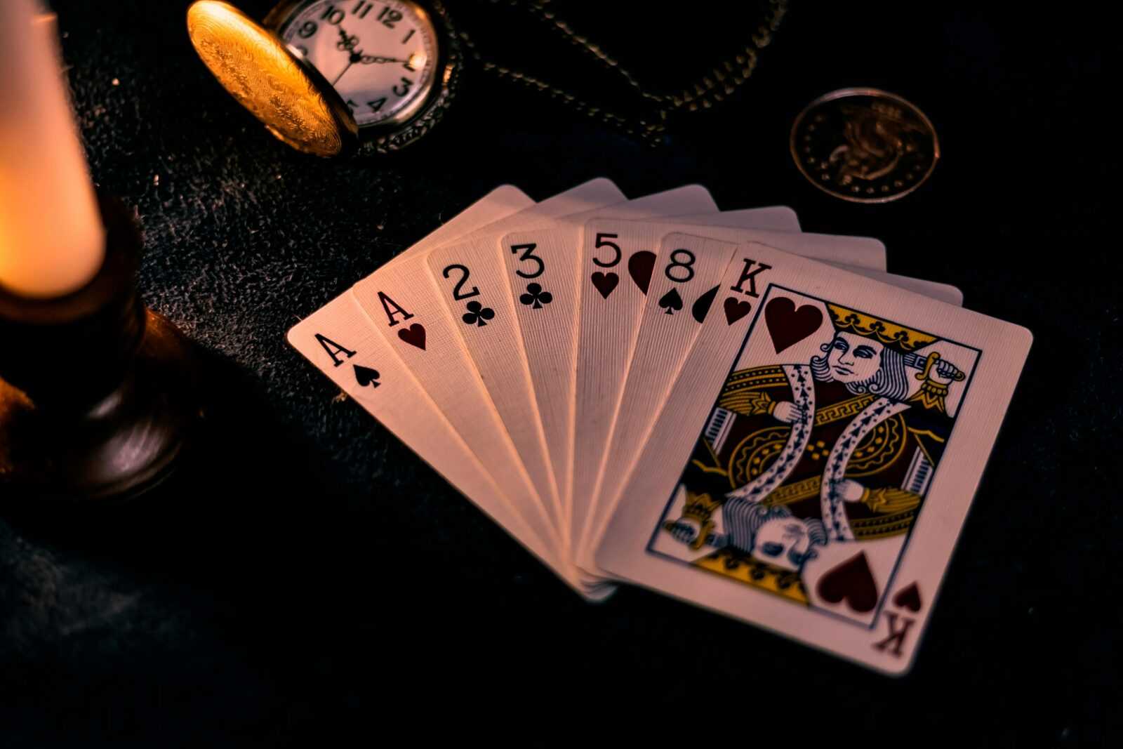 A dimly lit close-up of playing cards with a pocket watch, showcasing a nostalgic casino vibe.